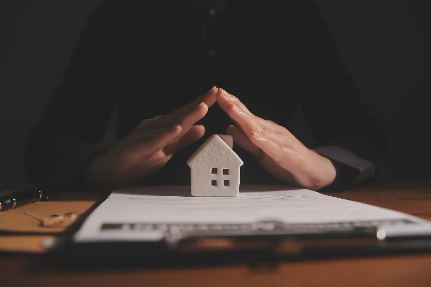 Hands held over a model house on a desk